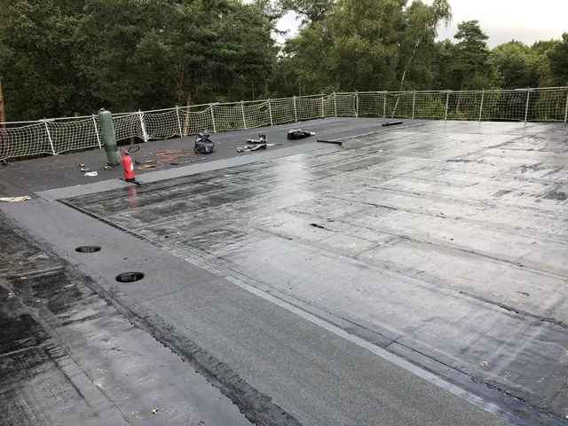 Pose du complexe d'étanchéité bitumineuse sur une grande toiture terrasse neuve