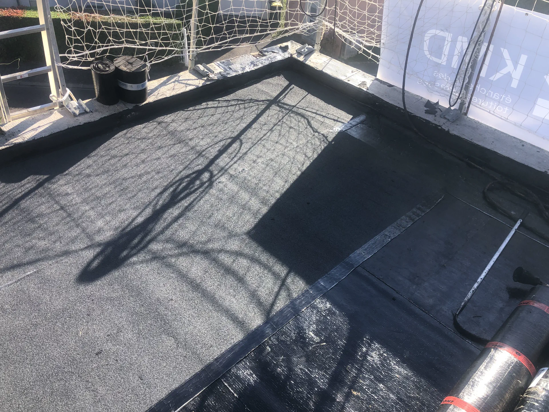 Chantier d'étanchéité KMD : membrane bitumineuse soudée en cours de pose sur une toiture terrasse